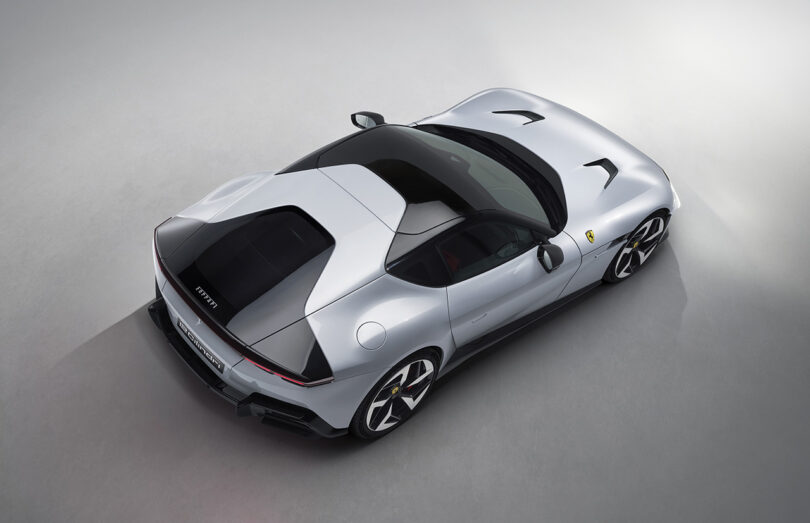 Top-down view of a silver Ferrari 12Cilindri sports car on a light gray surface, showcasing its sleek design and aerodynamic shape.