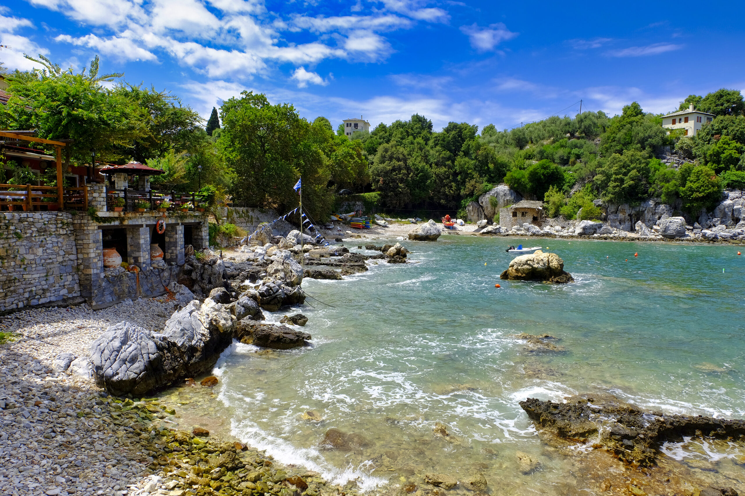 Stone buildings sit on the edge of a light blue coast. 