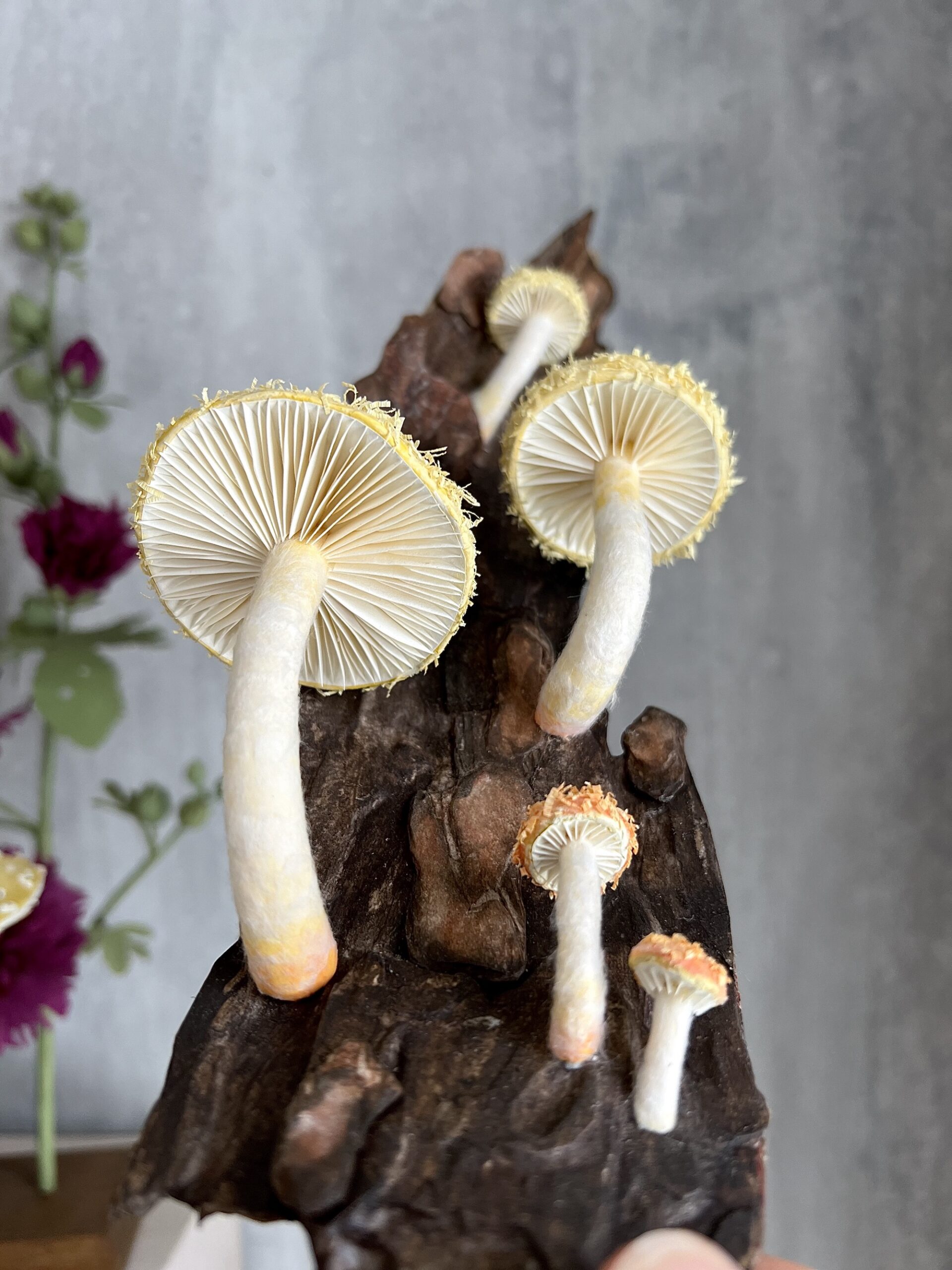 realistic yellow paper mushroom sculptures attached to a log, with emphasis on their gills