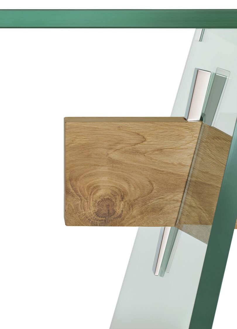 A wooden block attached to a glass dining table with metal brackets.