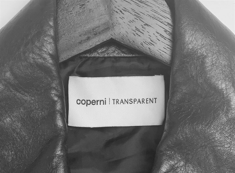 Black and white shot of the Coperni x Transparent Speaker Jacket sewn label; jacket is on a coat hanger.