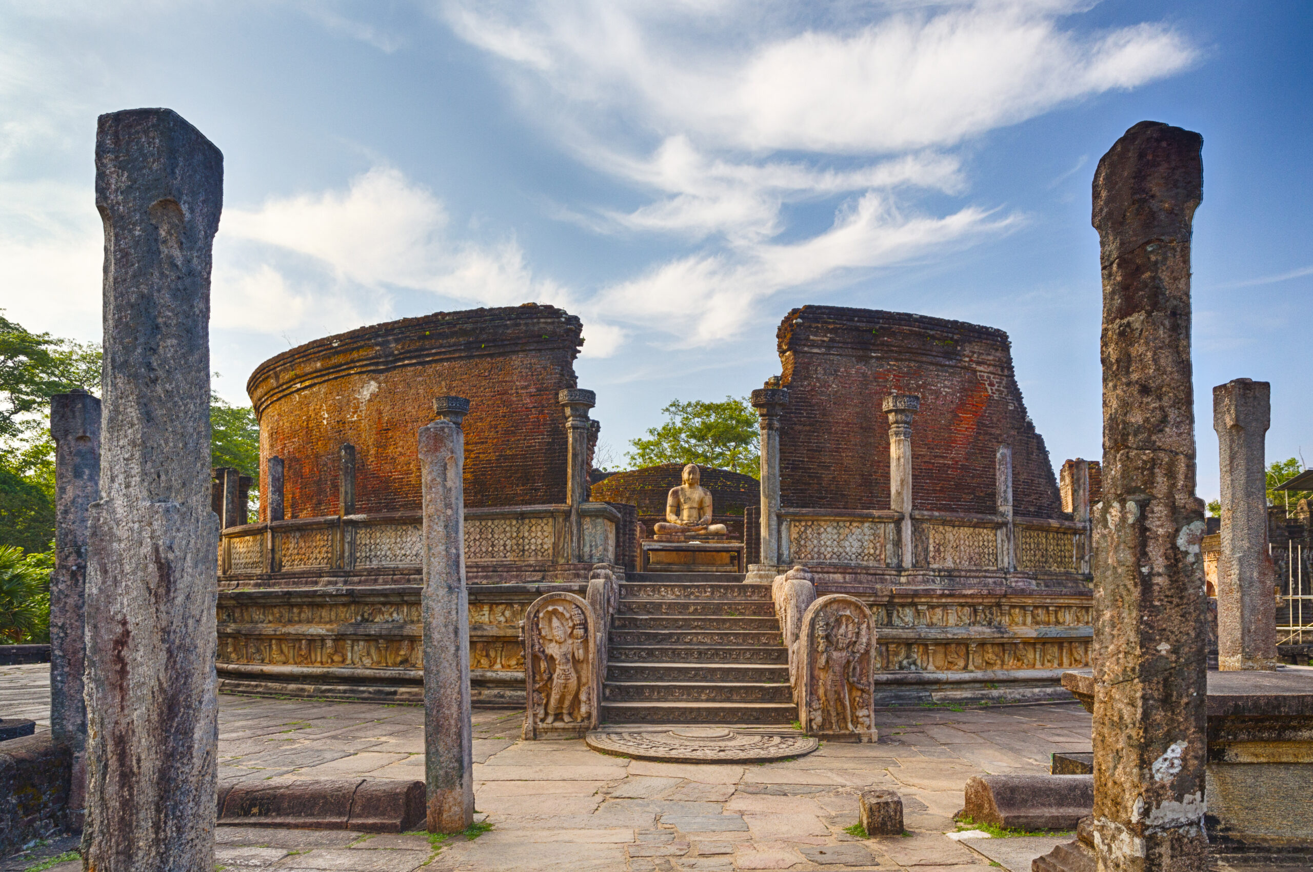 Polonnaruwa, Sri Lanka The crumbling brick walls and columns of a ruined temple with a buddha figure sat in the center