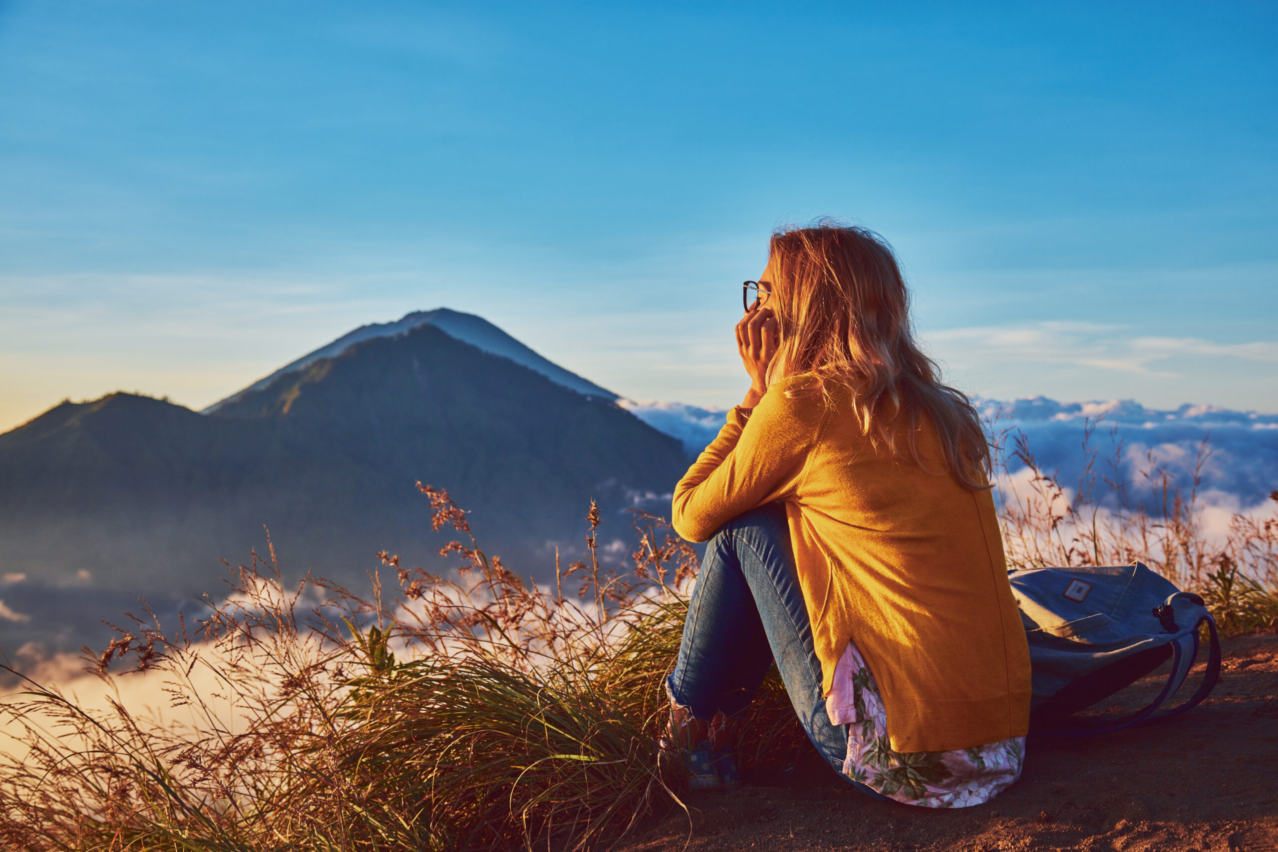 Woman watching the sun rise from the top of Mt Batur, Bali, Indonesia