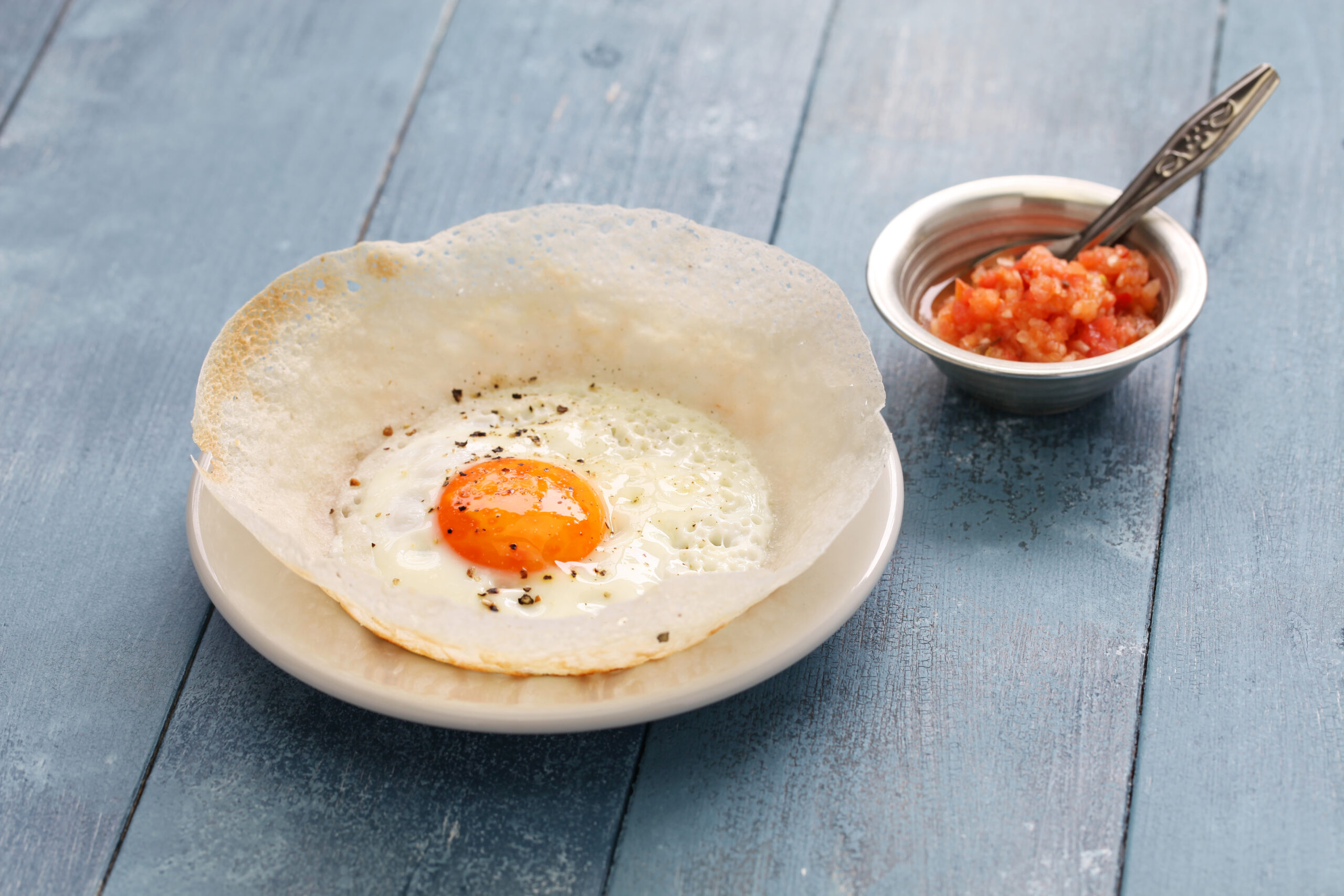 GettyRF543978524.jpg Sri Lankan egg hopper (bittara aappa) served on a plate.