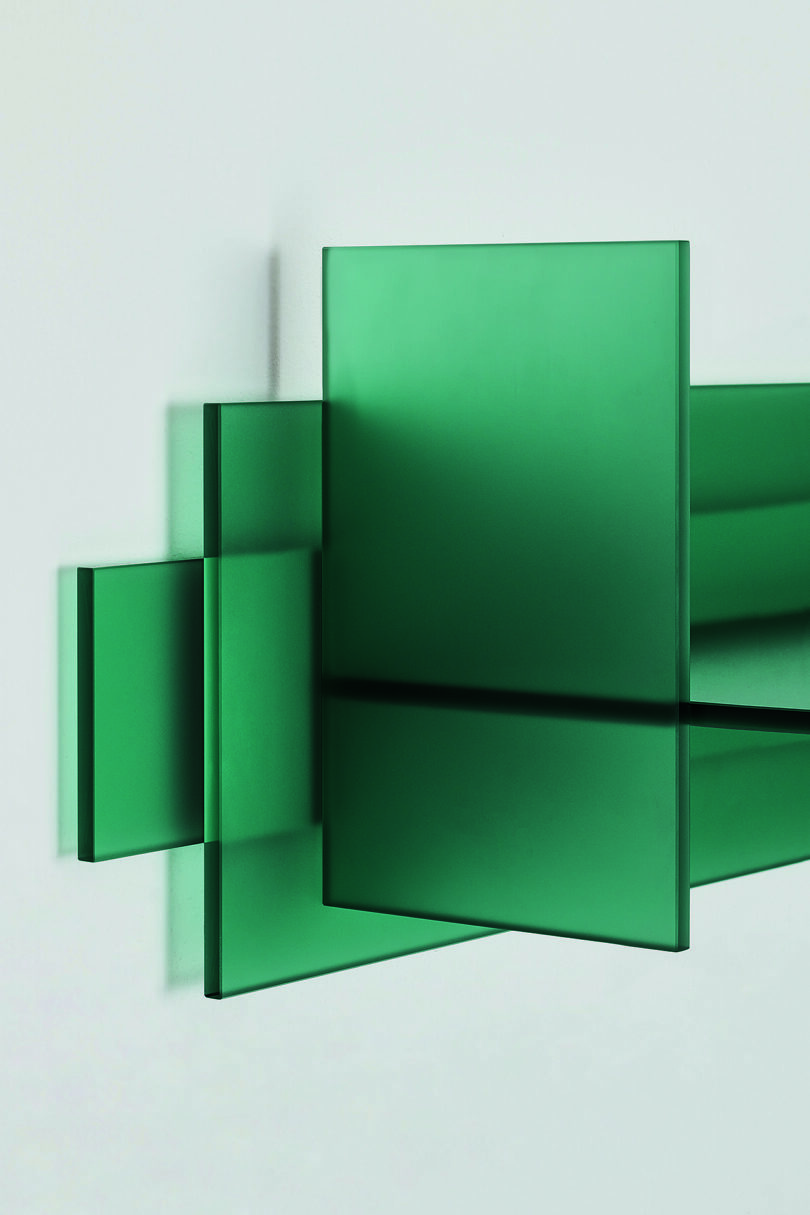 Detail of a minimalist green glass table displayed against a plain background.