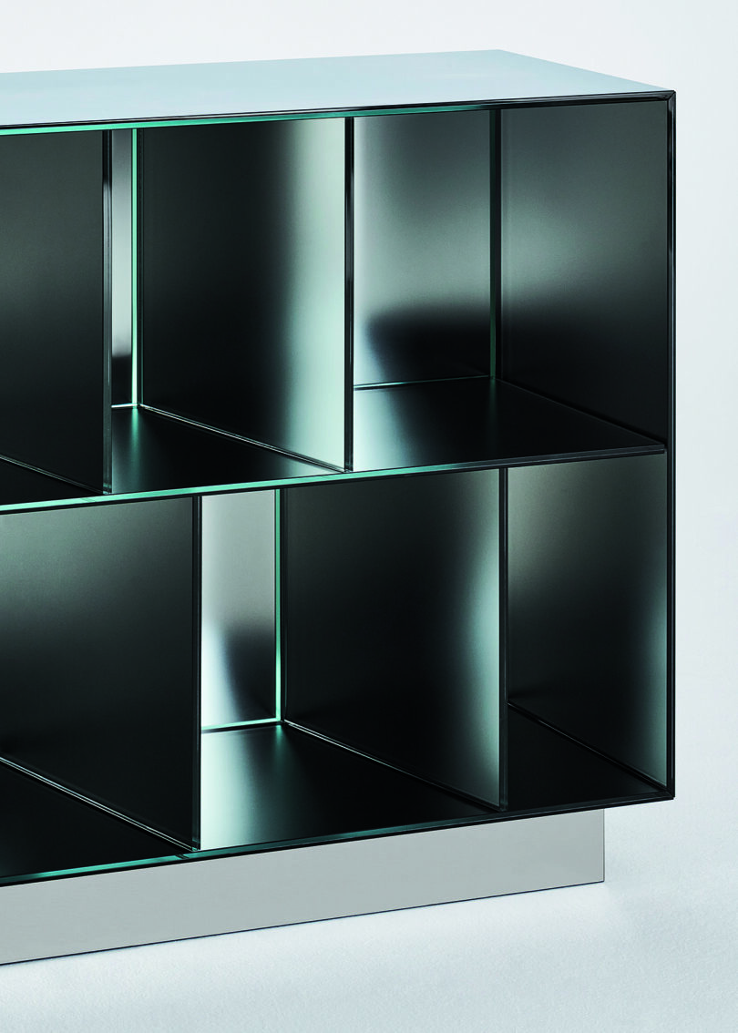 Detail of a modern metal storage unit with a geometric design featuring multiple square and rectangular compartments, positioned against a plain white background.