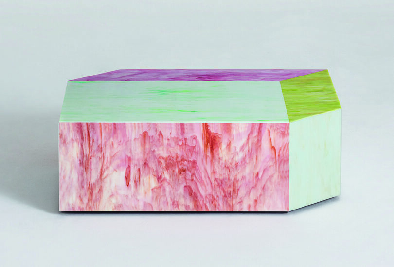 A multicolored geometric coffee table featuring shades of pink, green, and purple with a marbled texture on a plain background.