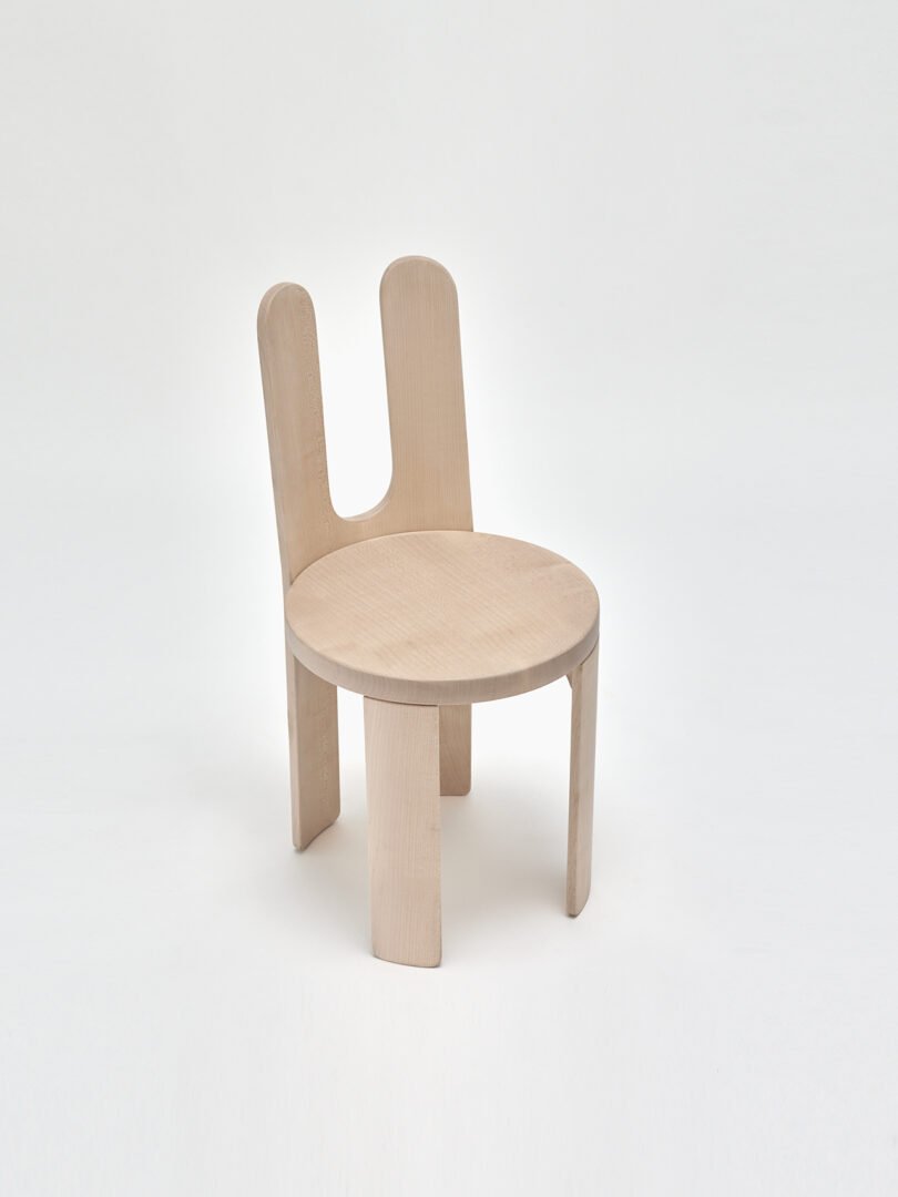 A modern chair with a light wood finish and a unique, dual backrest design.
