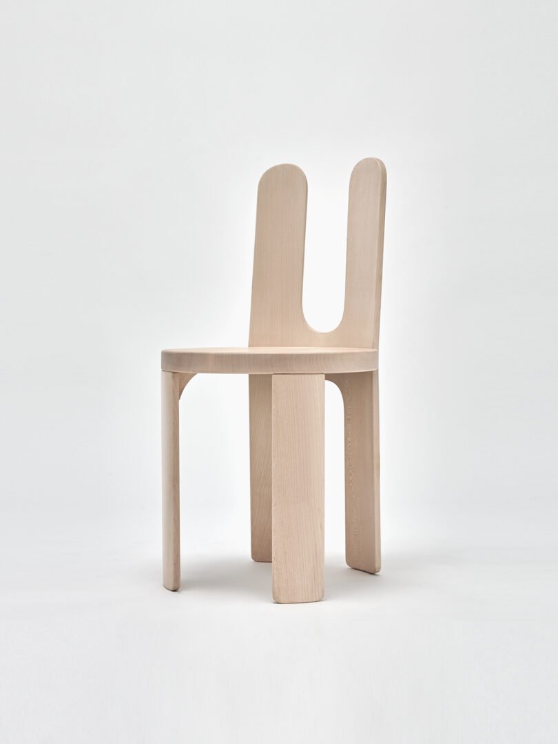 A modern chair with a light wood finish and a unique, dual backrest design.