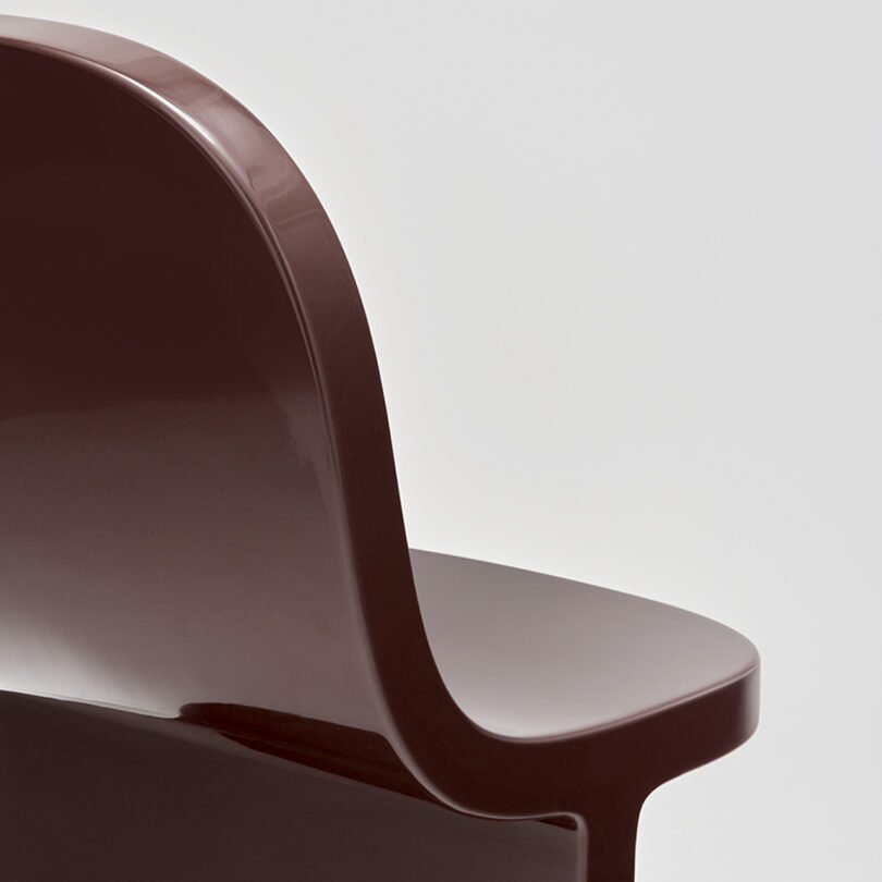 Close-up of a brown modern chair against a neutral gray background.