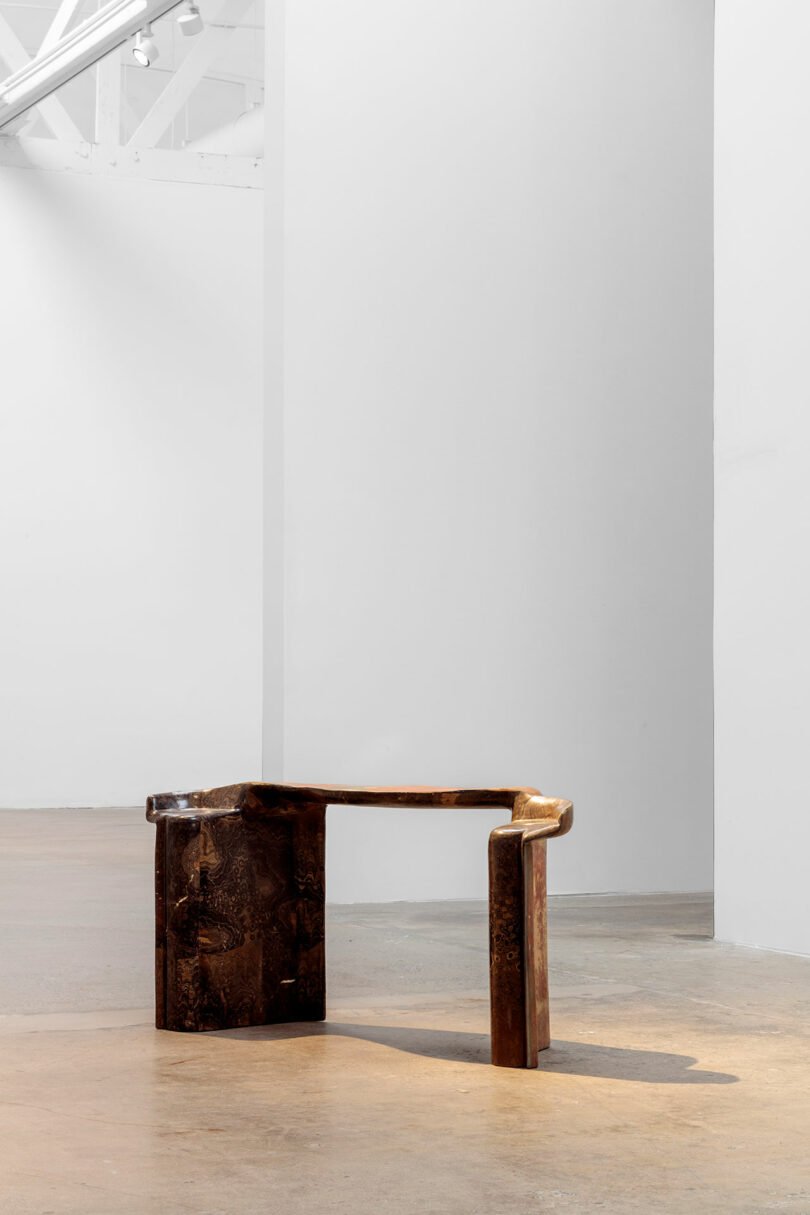 A unique, dark wooden chair with an asymmetrical design by Vincenzo De Cotiis is placed in an empty, well-lit white gallery space.