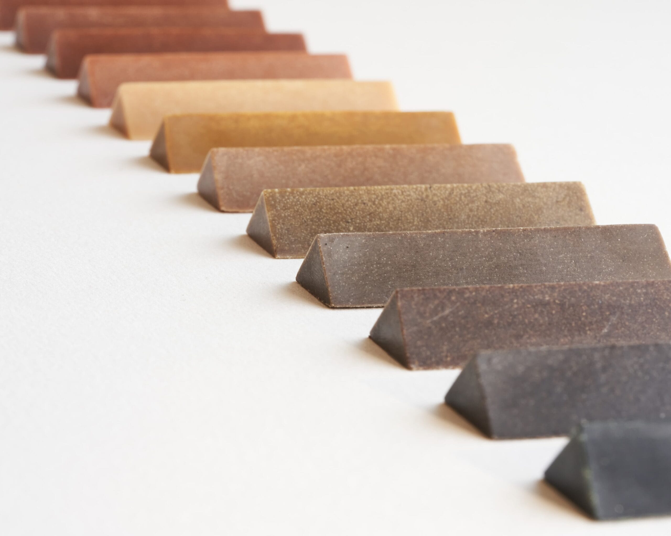 a row of colorful, triangular crayons made from the naturally occurring colors of wood from different trees