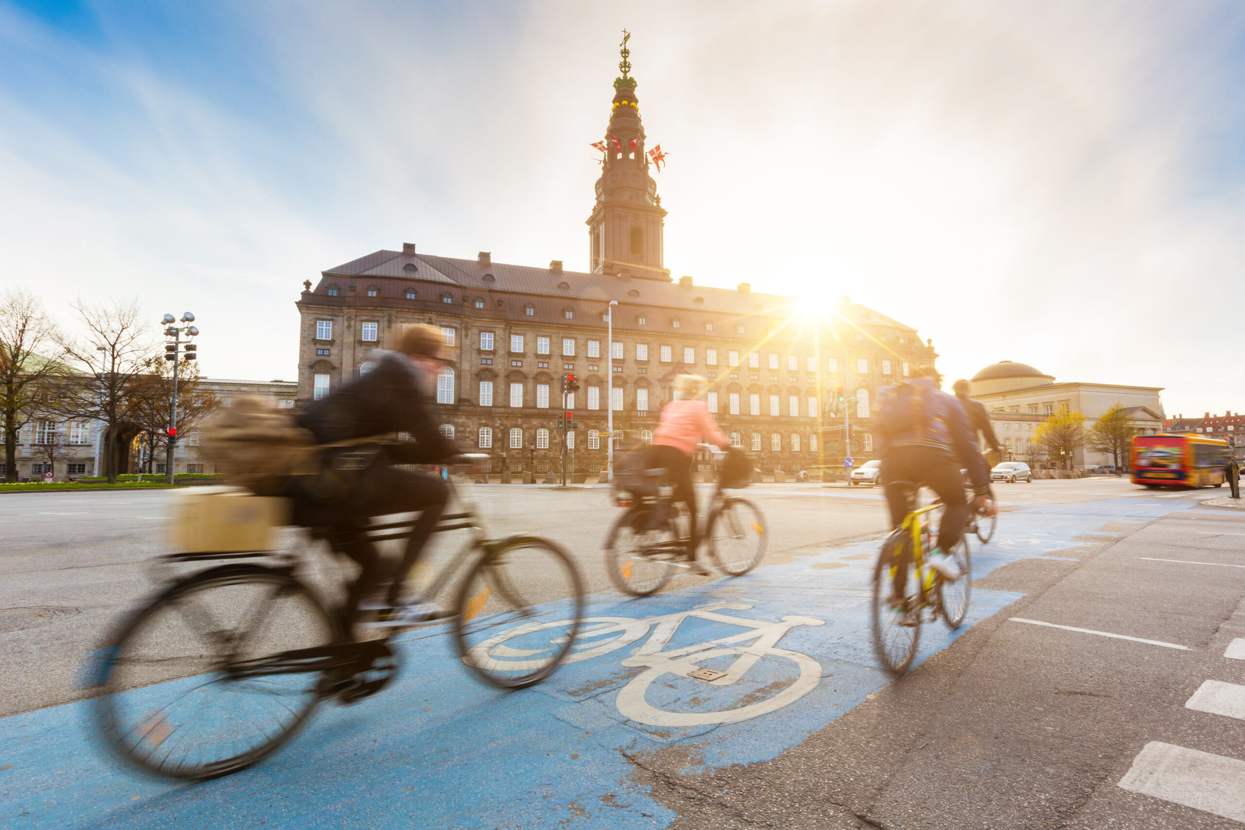 The tower of Christiansborg palace is the city's best free viewpoint Blurred cyclists ride on a bike lane in Copenhagen, with the sun setting over Christiansborg palace