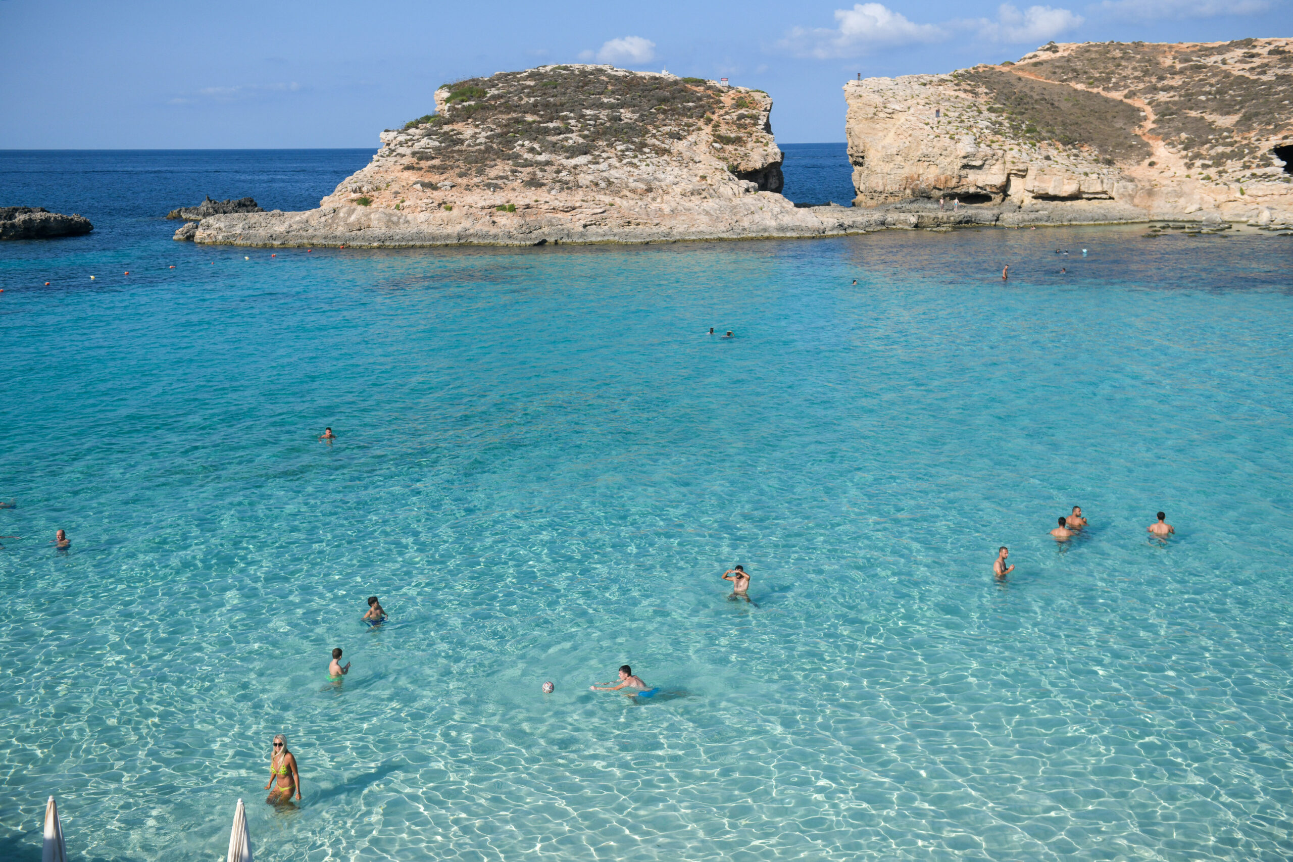 Malta-Comino-Blue-Lagoon People swim in the bright blue waters of Malta's Blue Lagoon.