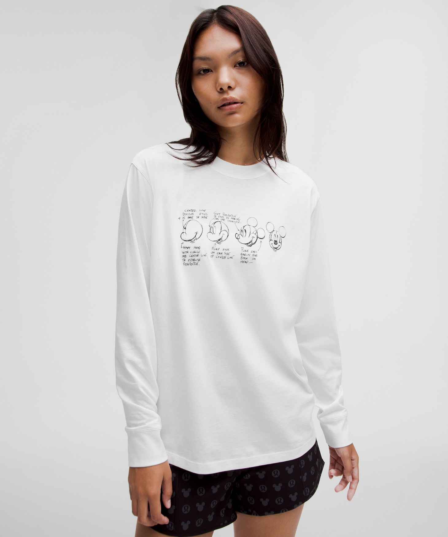 A woman wearing a white long sleeve t-shirt with a black illustration on it.