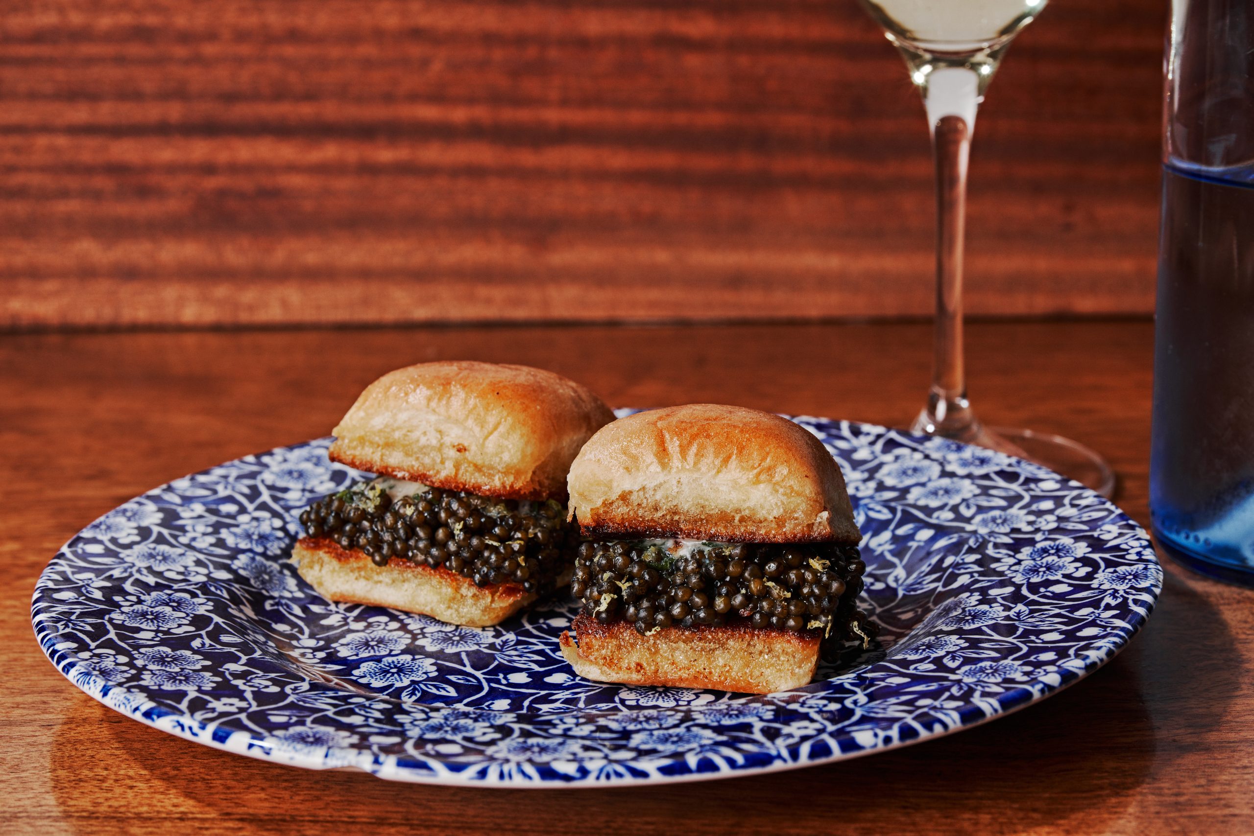 Two buns filled with caviar sit on a plate. 