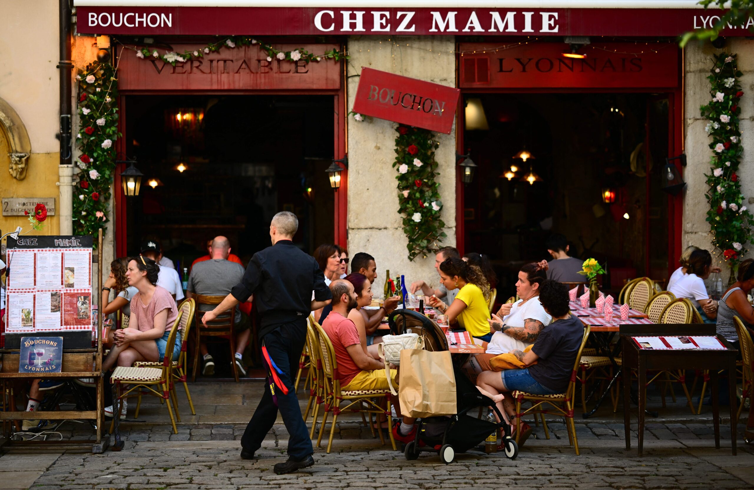 People eat at tables outside a Bouchon, a traditional Lyon restaurant, in the old city part of Lyon. 